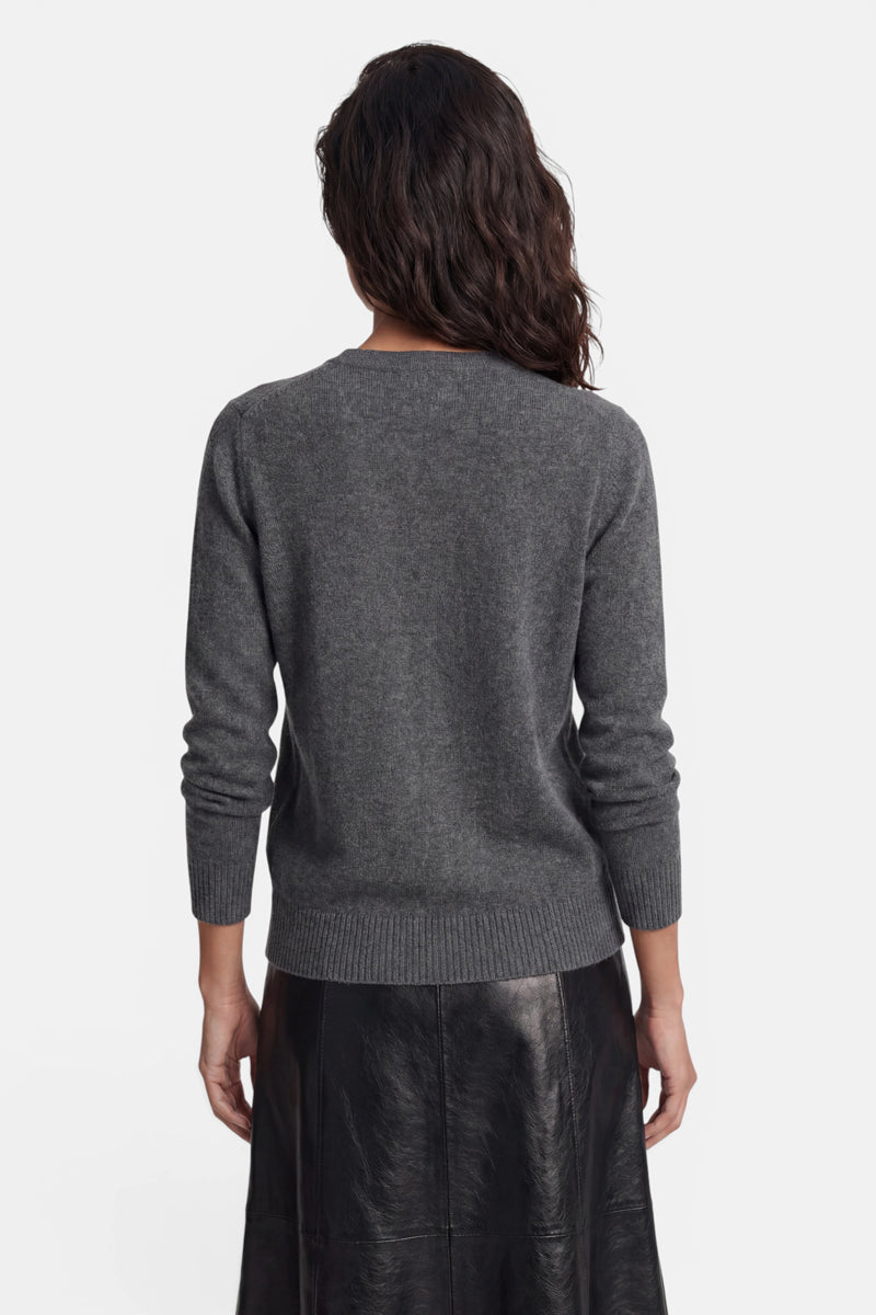 Eine Person, die von hinten zu sehen ist, trägt einen dunkelgrauen Langarmpullover mit geripptem Rundhalsausschnitt, gerippten Ärmelbündchen und geripptem Saum. Außerdem trägt sie einen schwarzen Lederrock vor einem schlichten weißen Hintergrund.