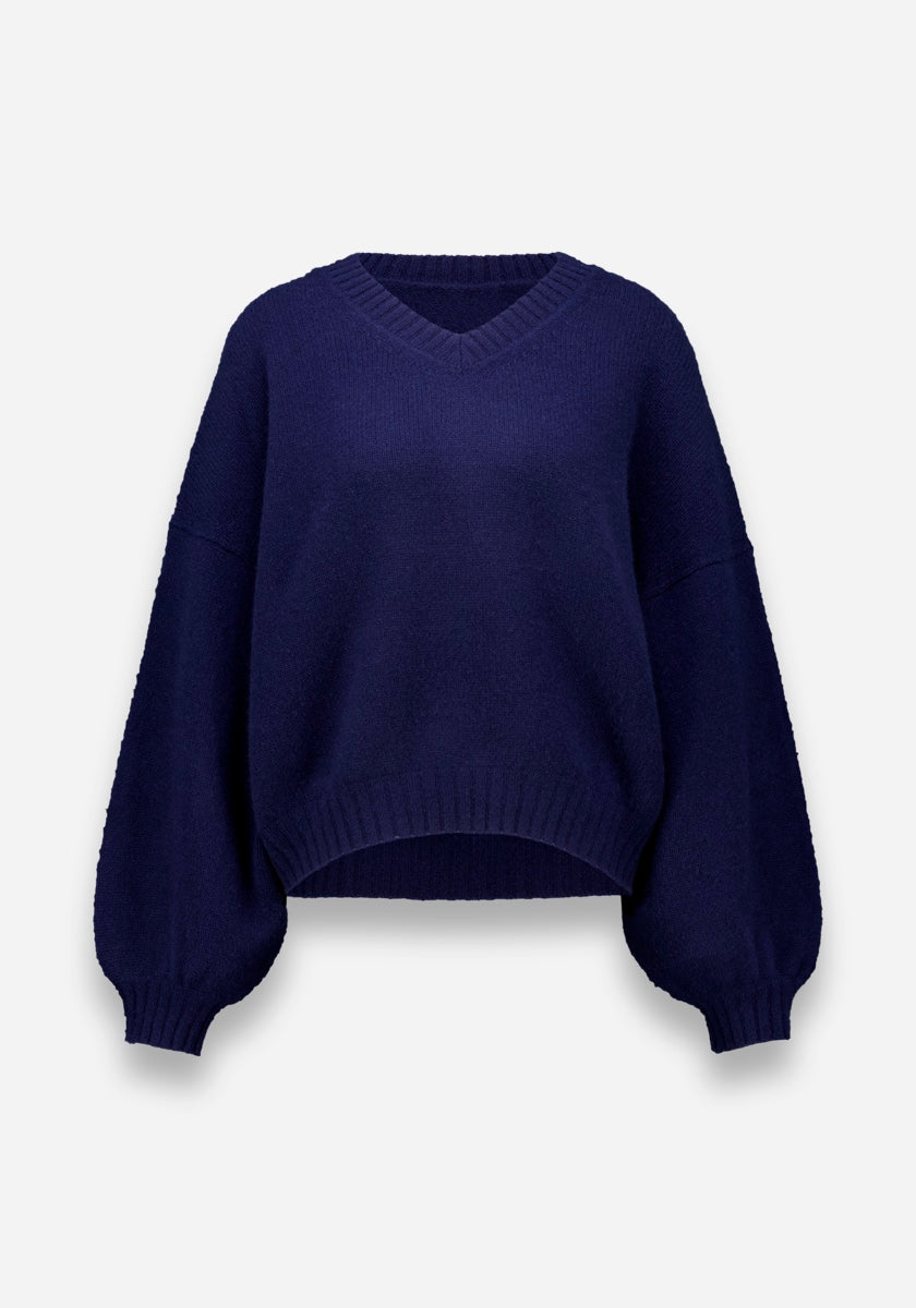 Marineblauer Princess Goes Hollywood Damen Kaschmirpullover mit langen Ärmeln, V-Ausschnitt, lockerer Passform, gerippten Bündchen und Saum, leicht ballonierten Ärmeln und einem vorne hochgezogenen Saum. Abgebildet auf einem einfarbig weißen Hintergrund.