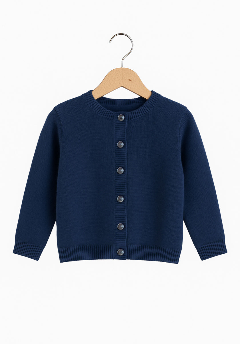 Eine marineblaue, langärmelige Princess Goes Hollywood Kaschmir Strickjacke Kinder mit Rundhalsausschnitt, Rippbündchen an Ärmeln und Saum und dunklen Knöpfen auf der Vorderseite wird auf einem Holzbügel vor einem schlichten weißen Hintergrund gezeigt.