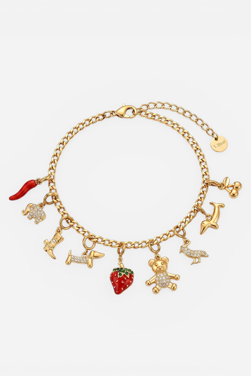 Das goldene „Princess Goes Hollywood“-Charm-Armband mit Kette und Karabinerverschluss verfügt über acht Charms – darunter einen Dackel und Erdbeeren, von denen einige mit Strasssteinen verziert sind –, ein rundes goldenes Anhängerchen und einen funkelnden Zirkonia-Anhänger.