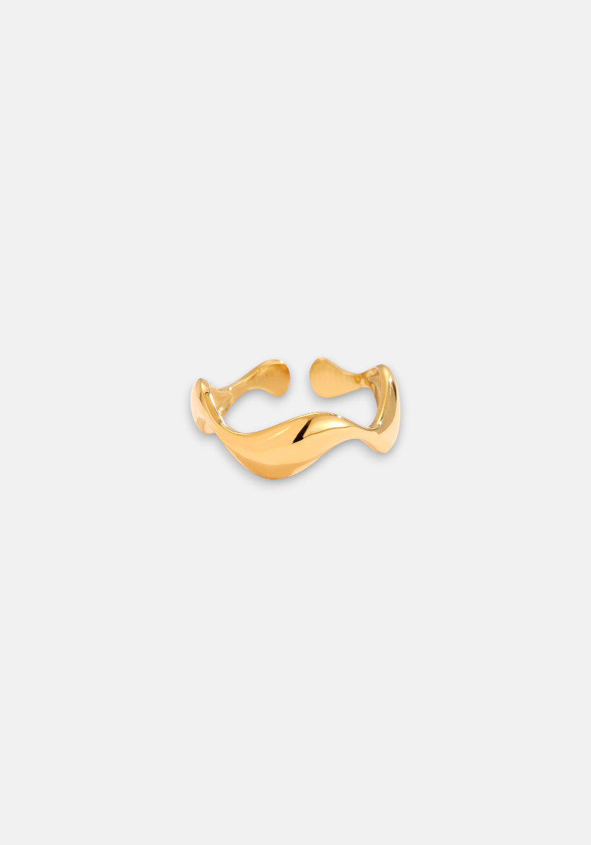 A Princess Goes Hollywood gold open ring with Gelbgold Vergoldung and a gently curving Edelstahl band rests on a plain light gray background, its shiny surface reflecting light and emphasizing its elegant, minimalist organic design.