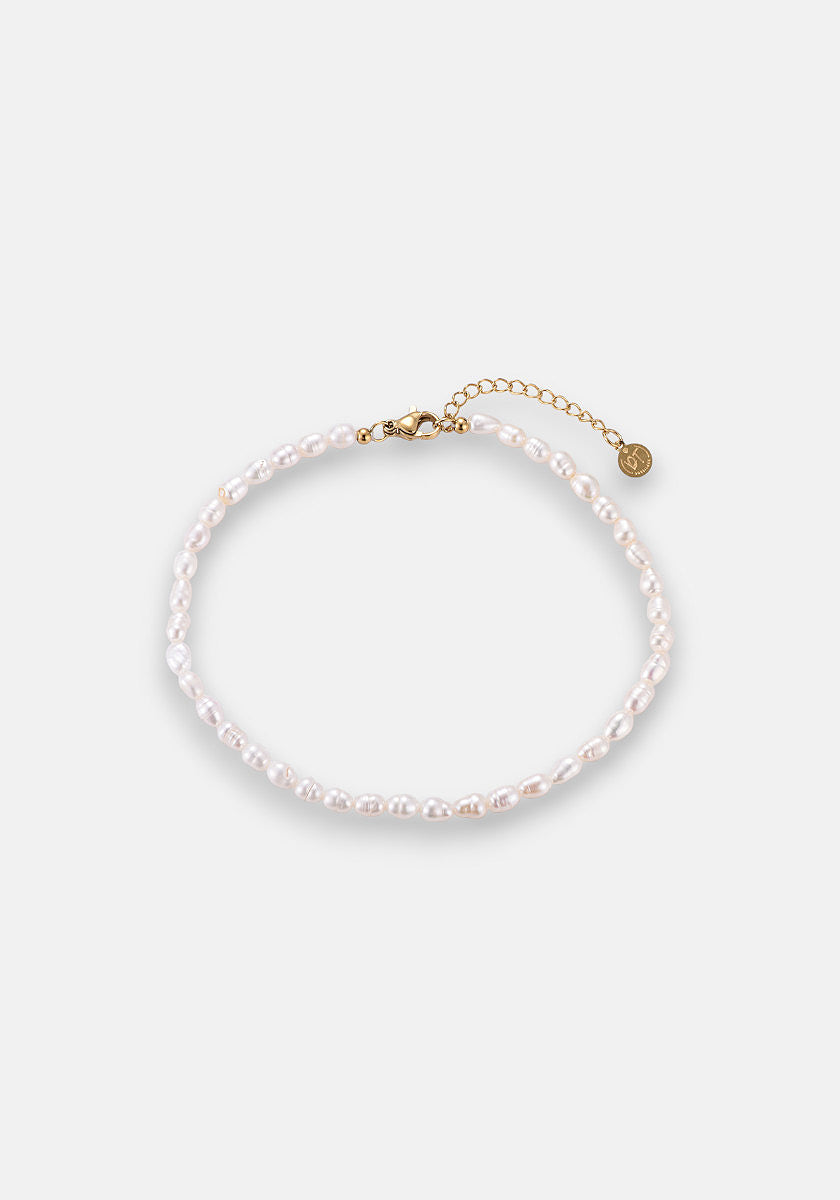A delicate Princess Goes Hollywood Fusskette Süsswasserperlen, crafted from small white pearls with a gold lobster clasp, adjustable gold chain, and a tiny round charm, is displayed in a loose circle on a plain white background.