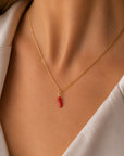 Nahaufnahme des Halses einer Frau, die eine goldene Kette von „Princess Goes Hollywood“ mit einem „Chili“-Anhänger als trendiges Accessoire trägt. Sie trägt ein weißes Hemd mit offenem Kragen, und ihr warmer Hautton unterstreicht den eleganten, minimalistischen Stil.