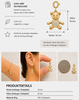 Ein funkelnder, mit Zirkonia besetzter goldener „Bär Charm“-Teddybär von Princess Goes Hollywood wird neben einer Münze als Größenvergleich gezeigt. Die Abbildung zeigt den Teddy als Ohrring und in einer Hand gehalten und gibt seine Maße an: 16 mm hoch, 14 mm breit. Der Text hebt Produktdetails wie die robuste Edelstahlkonstruktion, die Art des Verschlusses und Pflegehinweise hervor.
