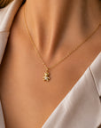 Eine Nahaufnahme einer Frau in einer cremefarbenen Bluse mit offenem Kragen und heller Haut, die eine goldene Halskette von „Princess Goes Hollywood“ mit einem funkelnden Schildkrötenanhänger trägt – ideal in Kombination mit Edelstahlschmuck wie dem „Bär“-Charm-Anhänger.