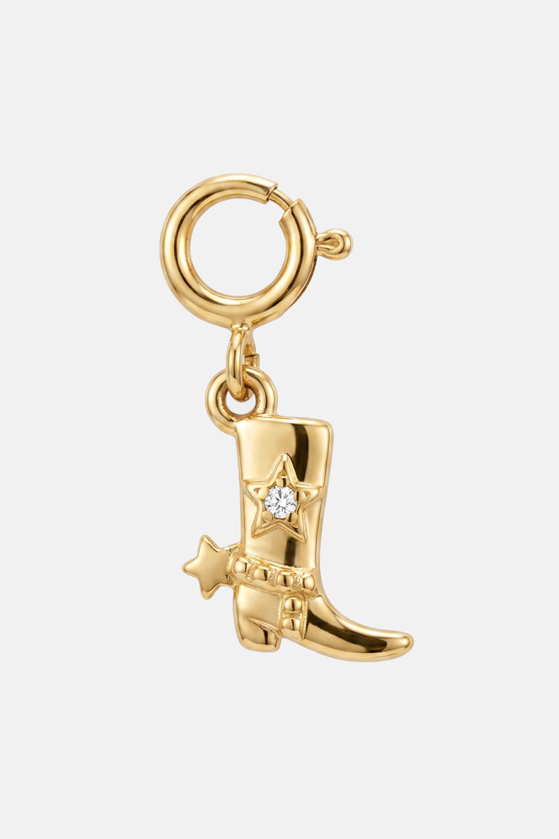 Der „Princess Goes Hollywood“-Anhänger in Form eines goldenen Cowboystiefels verfügt über einen runden Verschluss, einen sternförmigen Sporn, einen Zierstern mit klarem Zirkonia sowie polierte Edelstahloberflächen mit filigranen Details – alles vor einem schlichten weißen Hintergrund.