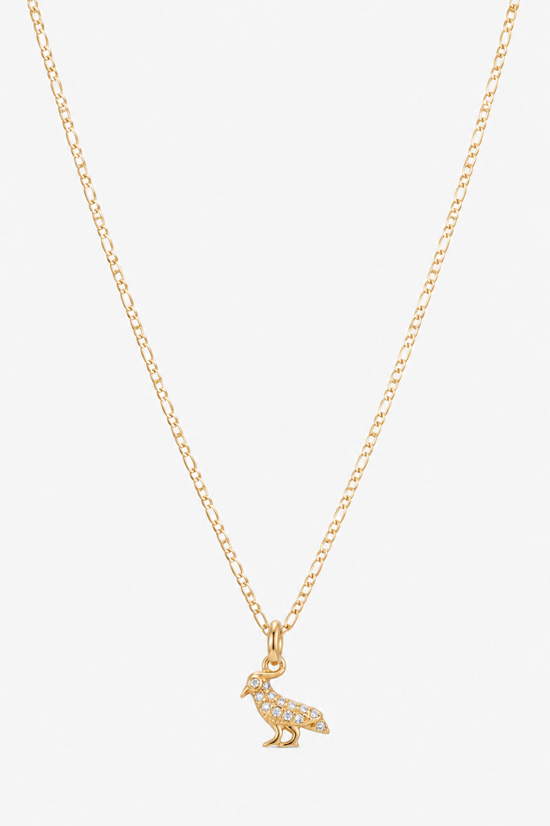 Eine zarte Goldkette von Princess Goes Hollywood ist mit einem funkelnden Vogel-Charm-Anhänger mit kleinen klaren Steinchen verziert. Das Schmuckstück wird vor einem schlichten weißen Hintergrund präsentiert, um die feinen Details dieses eleganten Schmuckstücks besonders hervorzuheben.