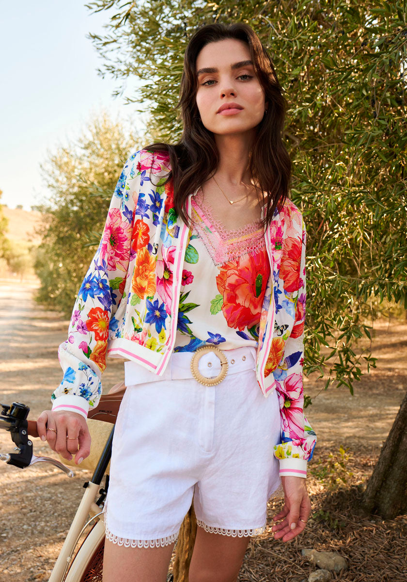 Lady wears white pants with floral open blouse and light top