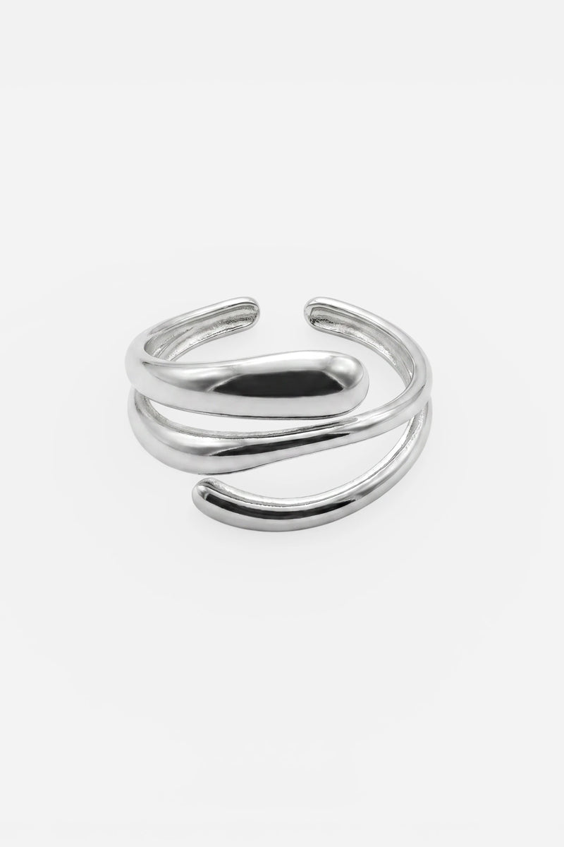 Ein glänzender silberner Edelstahlring von Princess Goes Hollywood mit offenem Banddesign und zwei eleganten, sich überlappenden Kurven, die sich an der Vorderseite ineinander verschlingen. Dieser verstellbare Ring besticht durch seinen minimalistischen Look und wird vor einem schlichten weißen Hintergrund fotografiert – ein perfektes Schmuckstück für Liebhaber von modernem Schmuck.