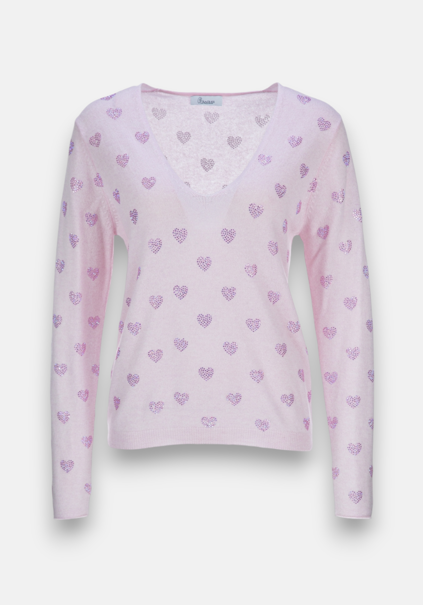 The Princess Goes Hollywood light pink fine knit sweater features long sleeves, a V-neck, a relaxed fit, and a sparkly purple heart motif. Crafted from soft wool-cashmere blend, it’s shown unworn against a plain white background.