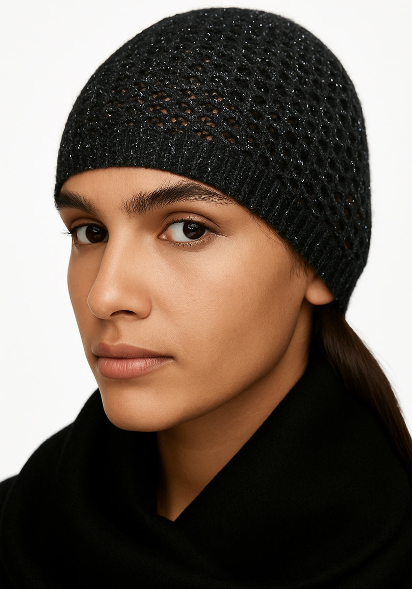 A person with medium skin tone and dark eyes wears a textured, dark Princess Goes Hollywood Strickmütze aus Merino-Alpaka-Mischung and a black scarf. Their hair is tucked inside the hat, with a neutral expression against a plain white background.