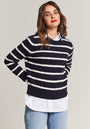 A woman with wavy brown hair and red lipstick stands against a neutral background, wearing a navy blue Princess Goes Hollywood Baumwolle Pullover with white stripes over a collared shirt, paired with light blue jeans.