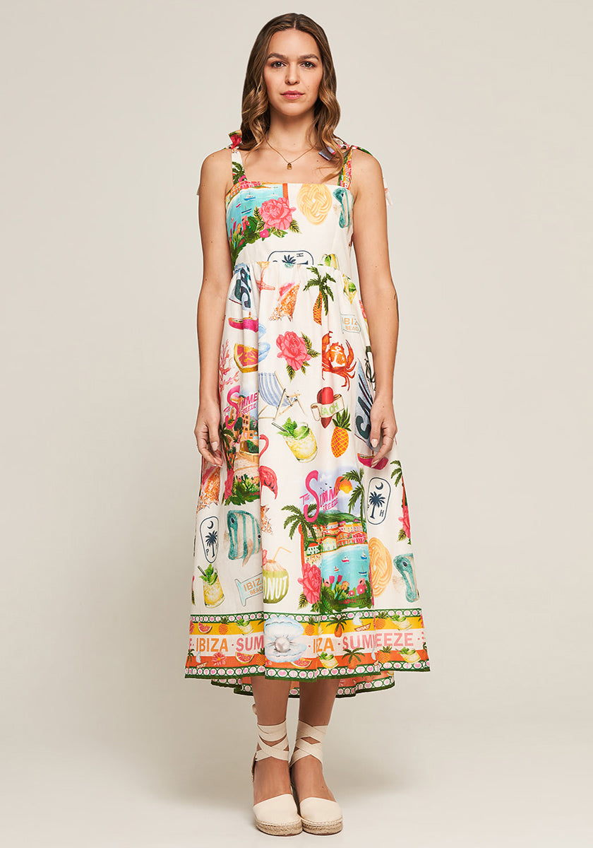 A woman with light brown wavy hair wears the sleeveless Midi Trägerkleid Summer Breeze by Frogbox by Princess, featuring a colorful floral and summer-themed print. She pairs it with espadrille shoes against a plain background.