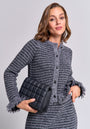 A woman with shoulder-length brown hair wears a gray bouclé button-up Strickjacke and matching skirt from Princess Goes Hollywood, holding a black quilted handbag under her arm, standing confidently against a plain light gray background.