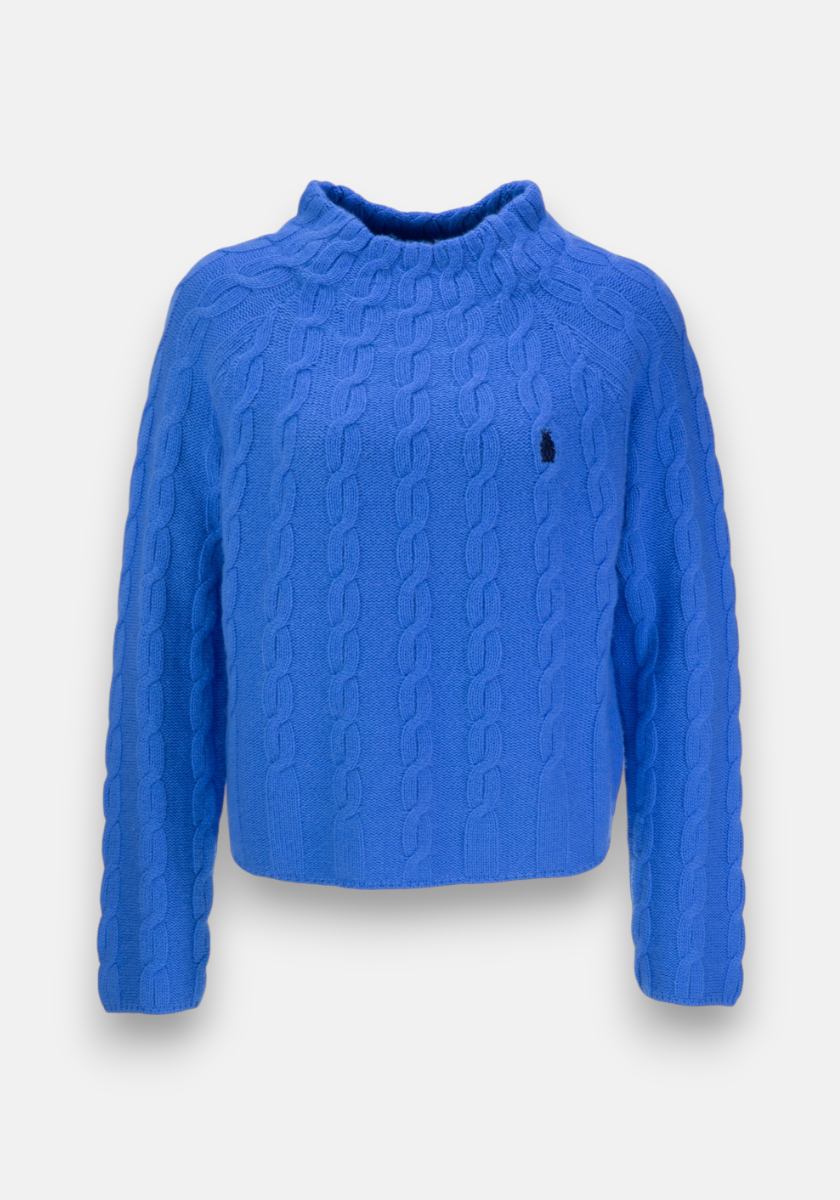 Ein leuchtend blauer Zopfstrick-Pullover von Princess Goes Hollywood aus Wolle-Kaschmir-Mix mit langem Arm, hohem geripptem Stehkragen, leicht verkürztem Schnitt und kleinem dunkel gesticktem Logo auf der linken Brust. Hintergrund: schlichtes Weiß.