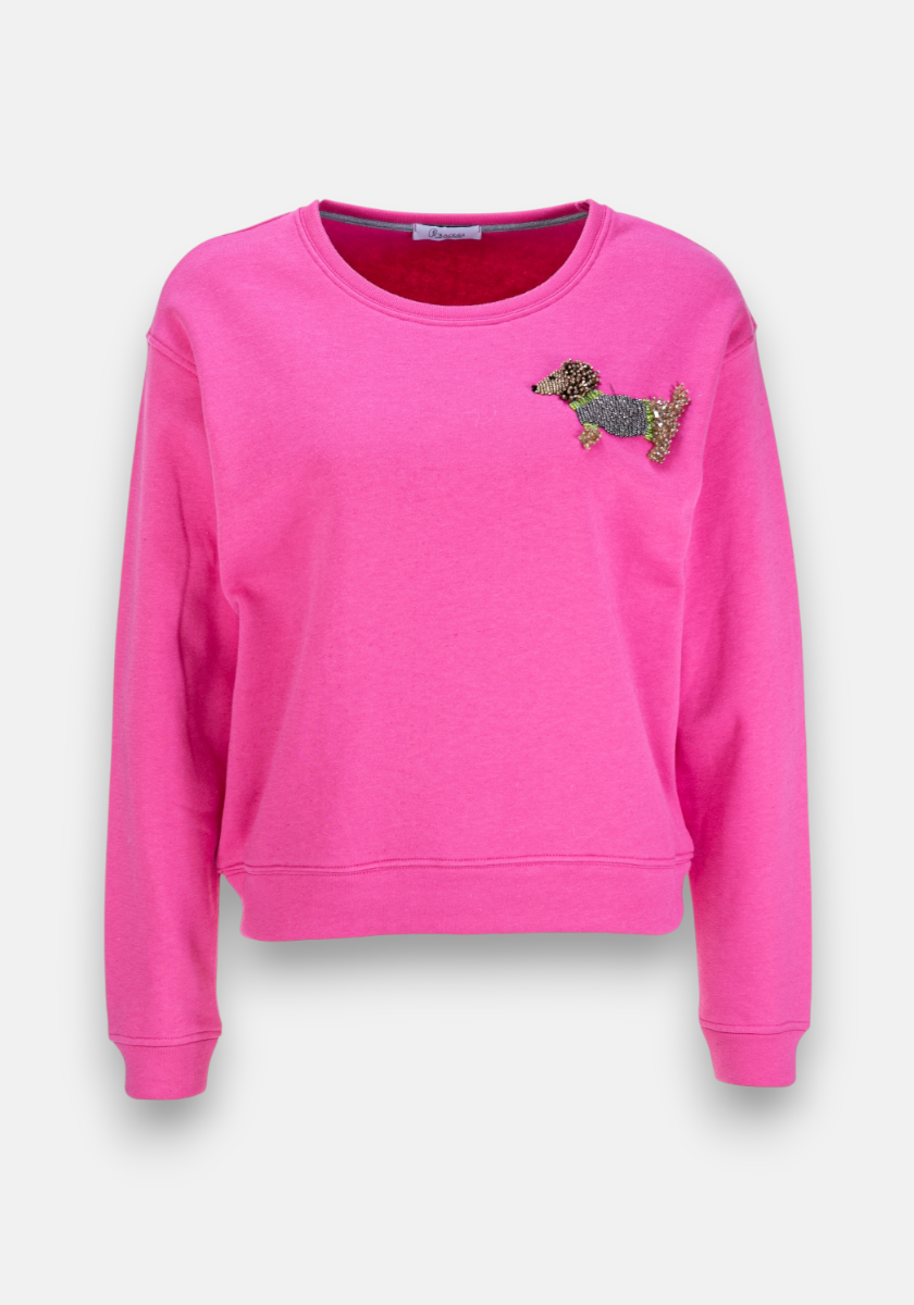 A bright pink long-sleeve sweatshirt from Princess Goes Hollywood features a round neckline and a black, brown, and gold Perlenstickerei Dackel-Motiv patch on the upper left chest. The item is shown on a plain white background.