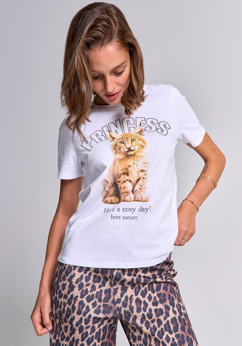A woman with light brown hair wears a weiße Baumwolle T-Shirt mit Rundhalsausschnitt von Princess Goes Hollywood, das ein flauschiges orangefarbenes Kätzchen und “PRINCESS” zeigt. Sie kombiniert es mit Luchs-Print-Hose vor hellem Hintergrund.
