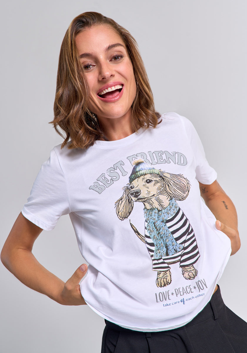 A smiling woman with shoulder-length brown hair wears a Princess Goes Hollywood Baumwolle T-shirt featuring a dachshund in a blue scarf and striped shirt, with "BEST FRIEND" above and "LOVE + PEACE + JOY, Take care of each other" below.