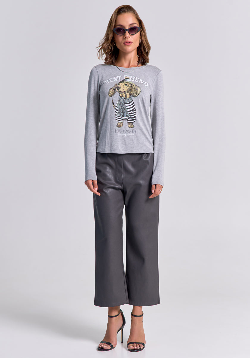 A woman faces forward against a plain background, arms relaxed, wearing Princess Goes Hollywood sunglasses, a light grey long-sleeve “BEST FRIEND” dog graphic shirt, wide-leg 7/8 Kunstlederhose with elastic waistband, and black heeled sandals.