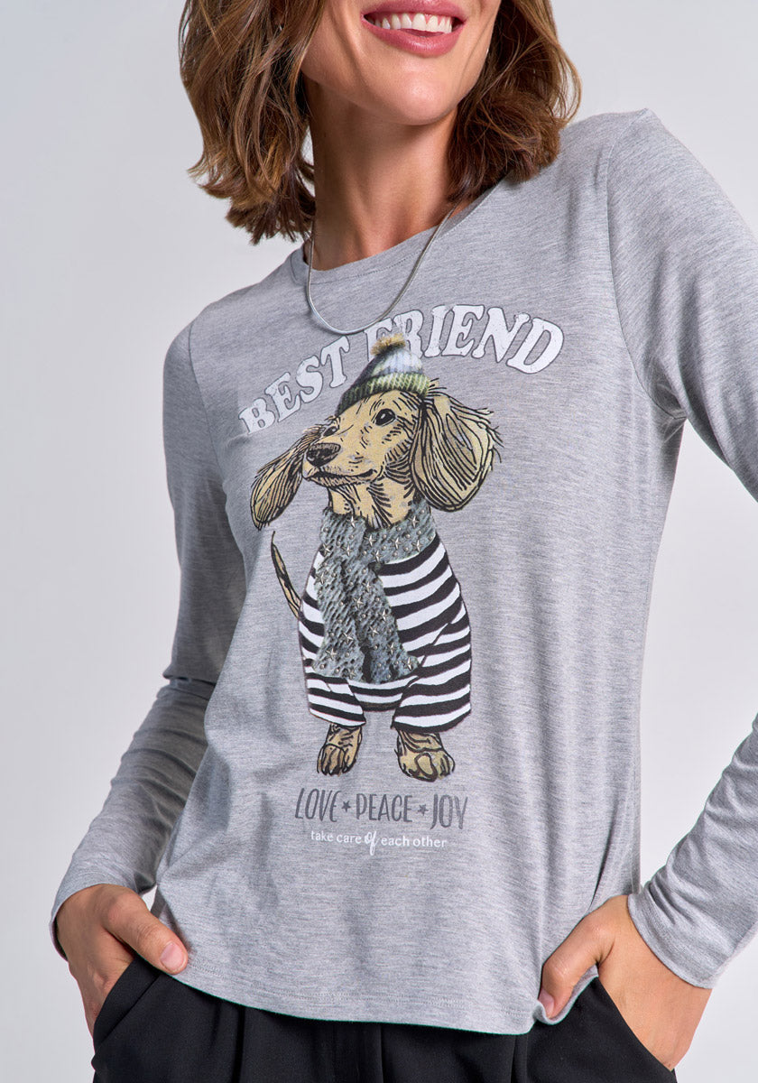 A woman with wavy brown hair wears a light grey Princess Goes Hollywood Langarmshirt with a charming Dackel-Print in a striped sweater and beanie. The shirt reads BEST FRIEND above the dog and LOVE • PEACE • JOY take care of each other below.