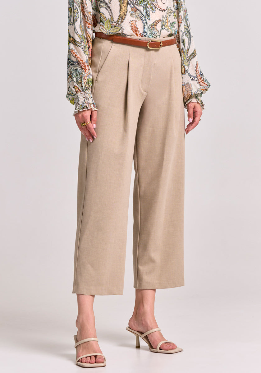 Eine Person trägt eine beige 7/8-Stoffhose mit weitem Bein von Princess Goes Hollywood, dazu einen braunen Gürtel, beigefarbene Heels und ein buntes Paisley-Oberteil mit voluminösen langen Ärmeln vor hellem Hintergrund.