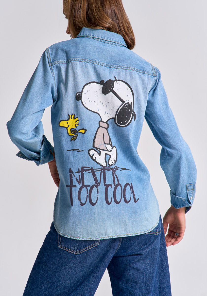 A person wears a light blue Princess Goes Hollywood Jeanshemd aus Baumwolle with a large Snoopy und Woodstock Stickerei on the back and “NEVER TOO COOL” lettering, standing hands on hips.
