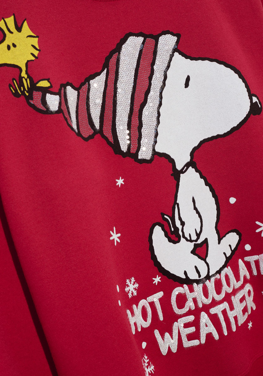 Der Princess Goes Hollywood Snoopy-Pullover aus rotem Stoff zeigt eine Zeichnung von Snoopy mit einer glitzernden, gestreiften Wintermütze, auf deren Spitze Woodstock zu sehen ist. Weiße Schneeflocken und der fette Text "HOT CHOCOLATE WEATHER" vervollständigen den festlichen Look.