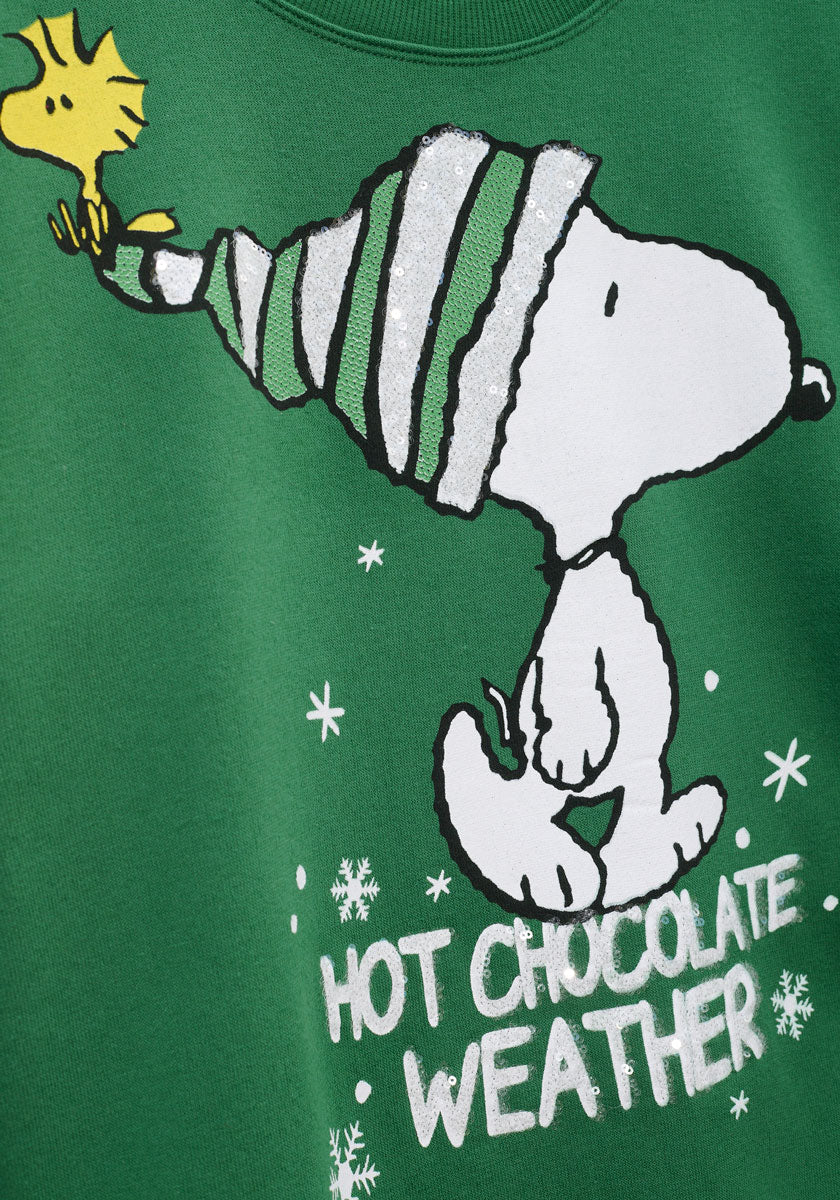 Dieser grüne Princess Goes Hollywood Snoopy Sweater zeigt Snoopy mit einer gestreiften Mütze und Woodstock, umgeben von Schneeflocken und dem Schriftzug HOT CHOCOLATE WEATHER - perfekt für einen festlichen Weihnachtslook.