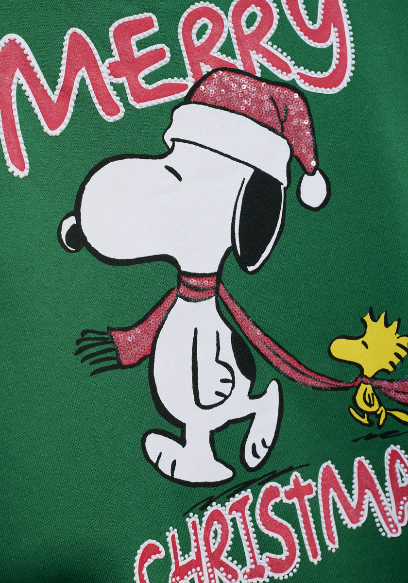Snoopy, mit glitzernder roter Weihnachtsmannmütze und Schal, geht stolz, während Woodstock mit dem Schal folgt. Der grüne Hintergrund und der fette Schriftzug "MERRY CHRISTMAS" machen diesen Princess Goes Hollywood-Pulli ideal für Snoopy-Fans!.