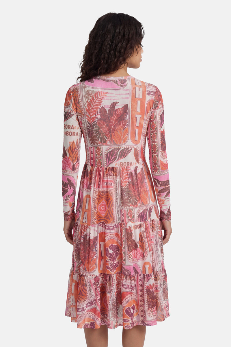 Eine Frau steht mit dem Rücken zur Kamera und trägt ein rosa-rotes „Princess Goes Hollywood“-Kleid mit Tahiti-Print aus Mesh, das mit auffälligen „TAHITI“- und „BORA BORA“-Schriftzügen verziert ist. Dieses langärmelige Kleid besticht durch ein figurbetontes Oberteil und einen gestuften, fließenden Rock, die ihm einen eleganten Look verleihen.