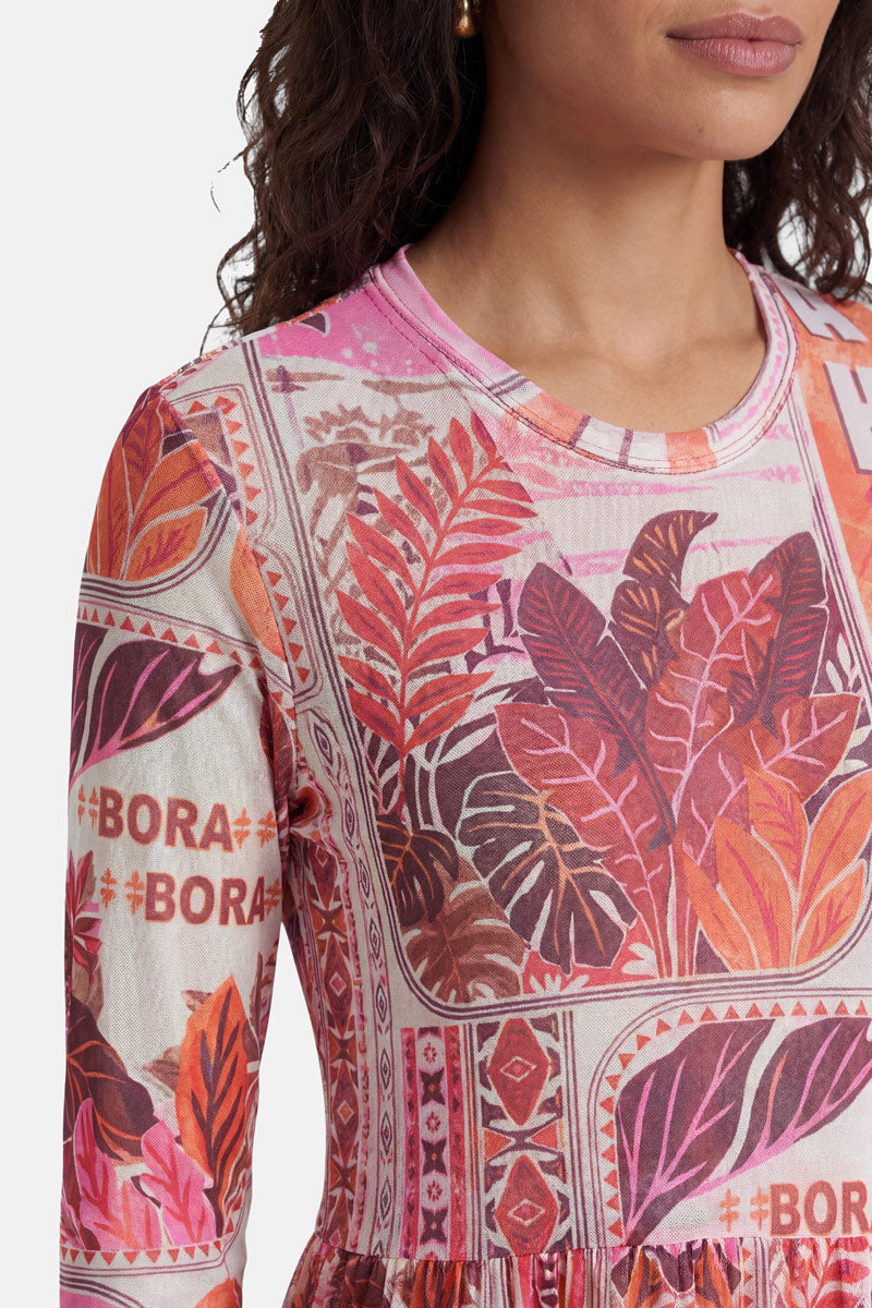 Eine Frau trägt ein langärmeliges Oberteil mit Rundhalsausschnitt von „Princess Goes Hollywood“ im Tahiti-Print, auf dem rosa, rote und orangefarbene tropische Blätter, geometrische Muster und wiederholte 