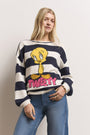 Eine Frau mit langen blonden Haaren trägt einen marineblau-weiß gestreiften Princess Goes Hollywood-Pullover mit einer handintarsierten Tweety-Grafik und einem fetten rosa "TWEETY"-Schriftzug, gestylt mit Blue Jeans und Goldschmuck vor einem hellen Hintergrund.