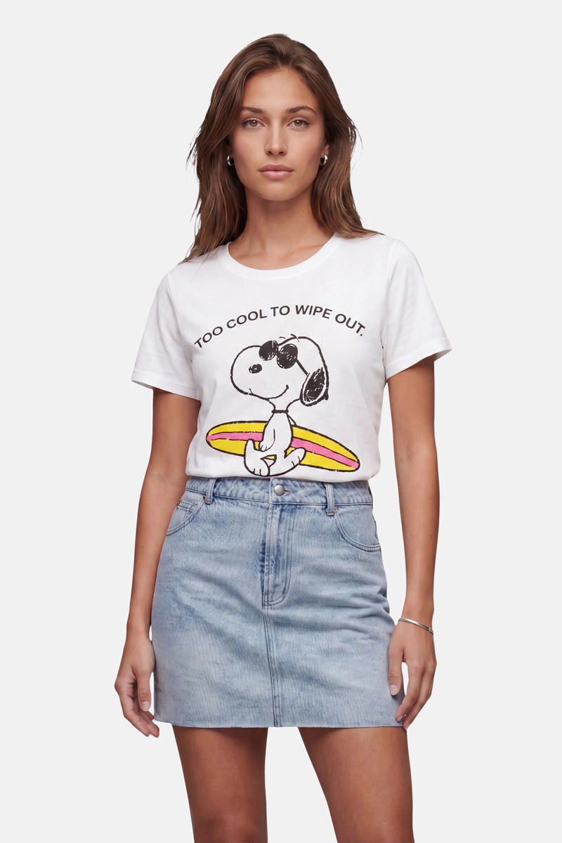 Eine Frau mit hellbraunen Haaren trägt ein T-Shirt von Frogbox by Princess in limitierter Auflage mit Snoopy-Aufdruck aus Baumwolle, auf dem Snoopy mit Sonnenbrille und Surfbrett zu sehen ist, begleitet von der Aufschrift „TOO COOL TO WIPE OUT“, dazu einen hellblauen Jeansrock vor weißem Hintergrund.