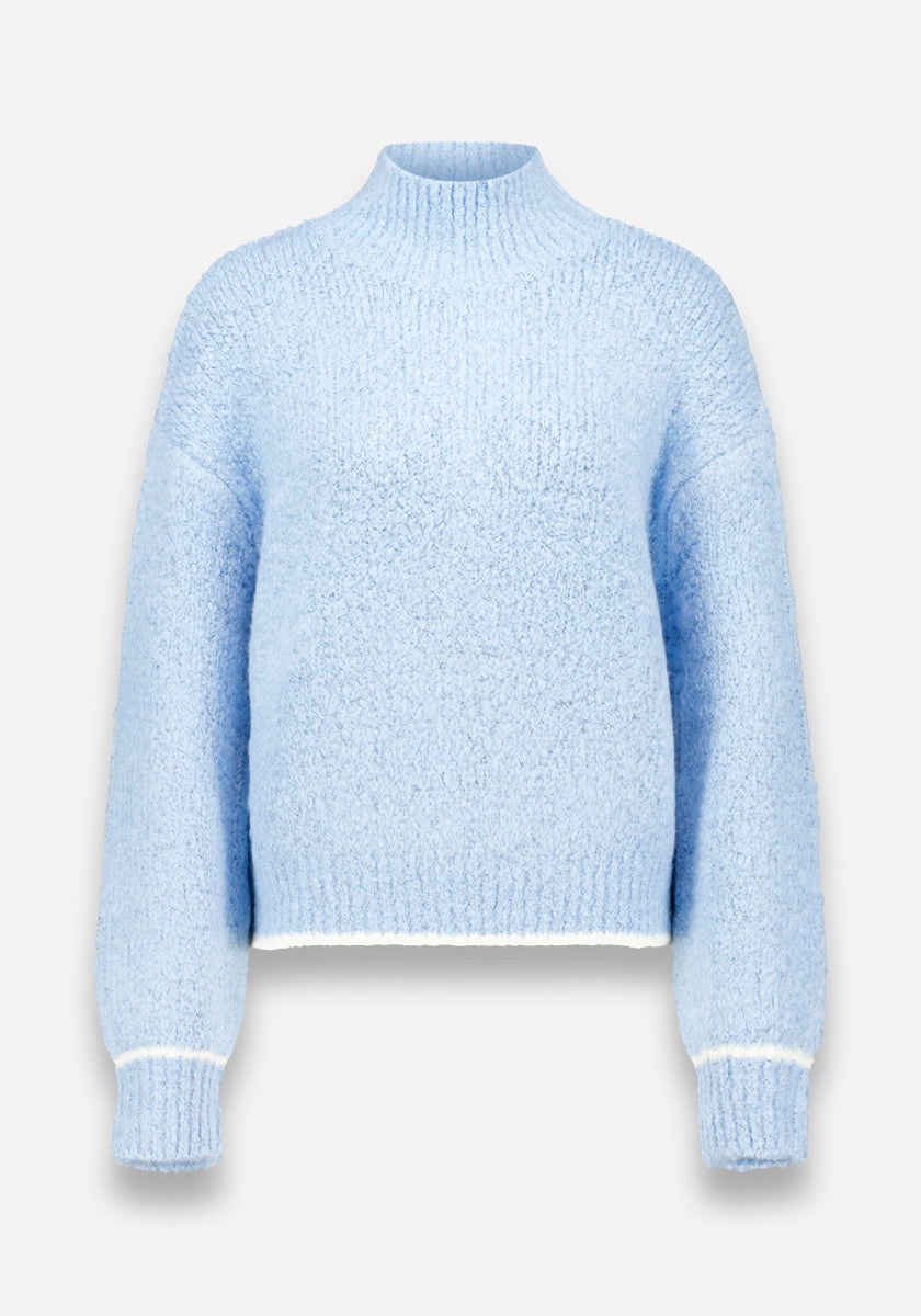 Der weiche, hellblaue Grobstrickpullover von Princess Goes Hollywood hat einen Stehkragen, lange Ärmel, gerippte Bündchen und einen Saum mit dezenten weißen Abschlüssen und eine lockere Passform durch den flauschigen Strukturstrick. Abgebildet auf einem einfarbig weißen Hintergrund.