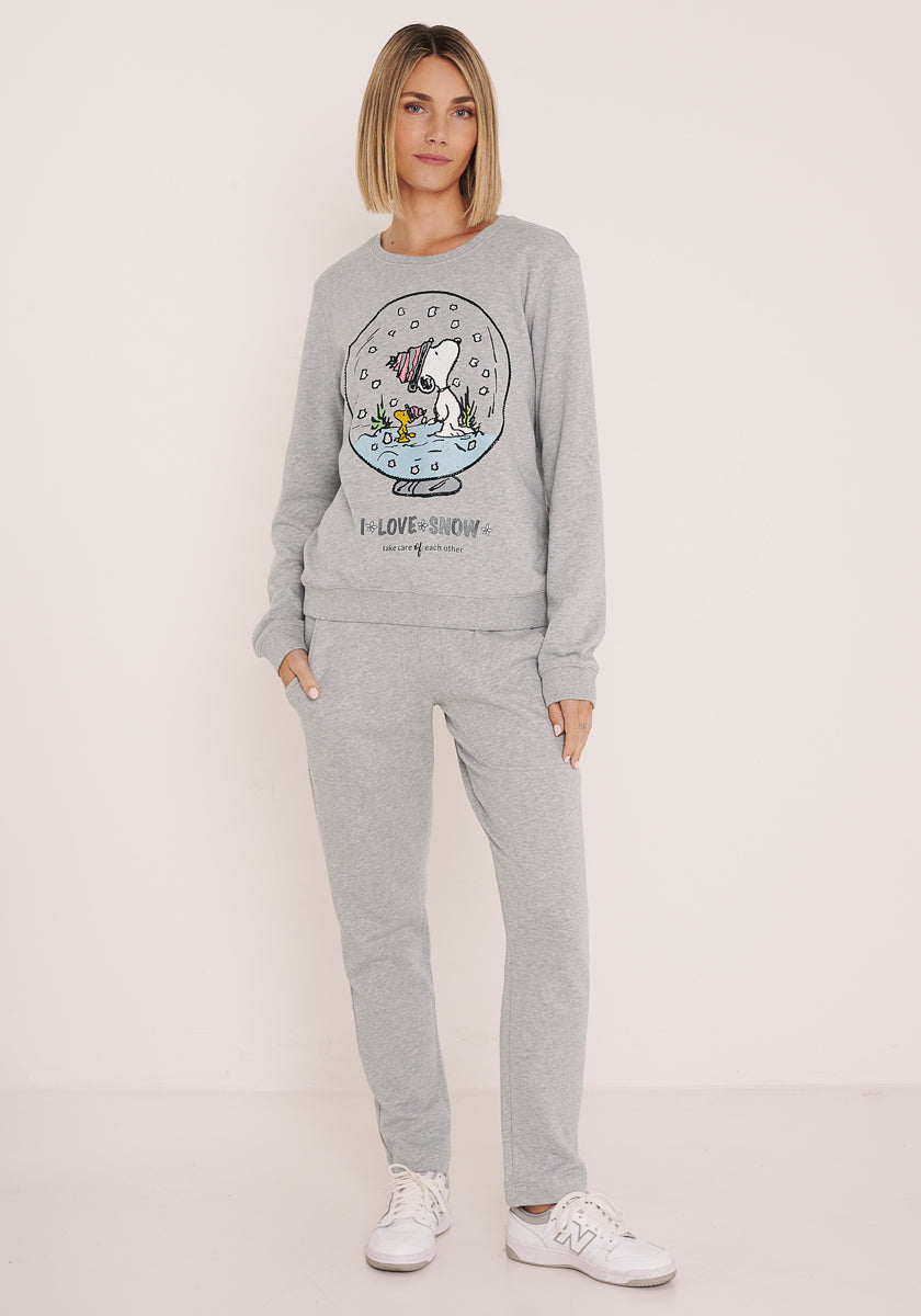 Eine Frau trägt einen hellgrauen Princess Goes Hollywood Baumwolle Damen Sweatsuit mit einem bunten Kaninchen in einer Schneekugel und &quot;I Love Snow&quot; auf dem Sweatshirt. Sie trägt dazu weiße Turnschuhe und hat glattes, schulterlanges Haar.