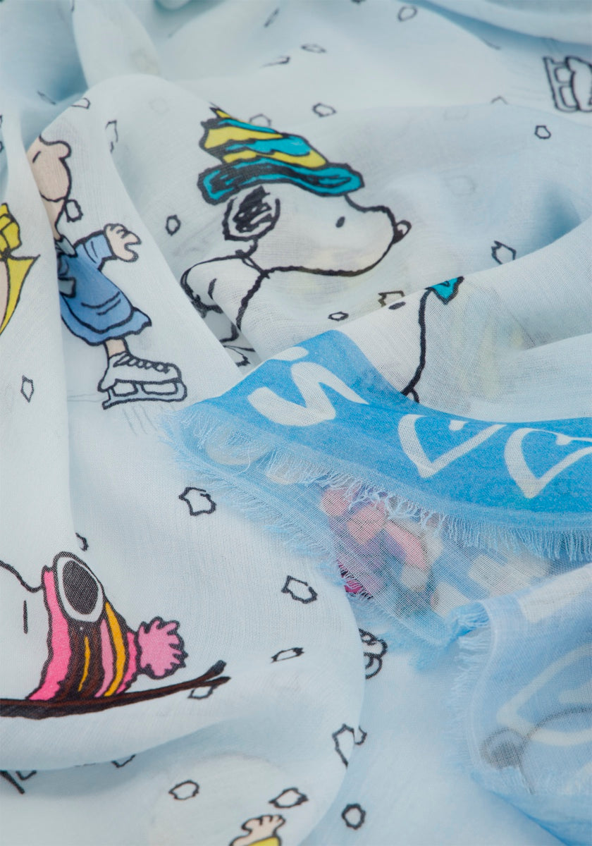 Eine Nahaufnahme eines Princess Goes Hollywood-Tuchs mit einem winterlichen Snoopy-Aufdruck, auf dem Snoopy und seine Freunde mit Hüten Schlittschuh laufen. Der hellblaue quadratische Schal zeigt weiße Schneeflocken, ausgefranste Ränder und einen Teil einer blauen Bordüre.