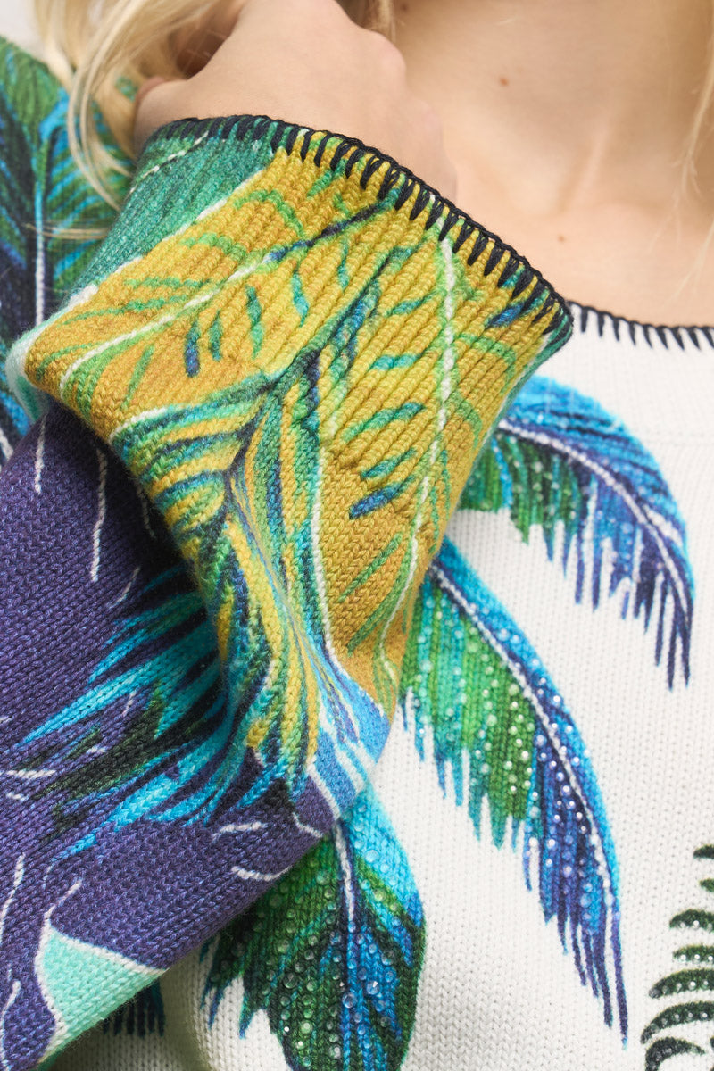 Nahaufnahme des Oberkörpers und des Arms einer Person, die einen Baumwollpullover von Princess Goes Hollywood mit einem leuchtenden Karibik-Druck in Grün, Gelb und Blau trägt. Das Ärmelbündchen ist umgeschlagen, und der Pullover hat kontrastierende Nähte am Halsausschnitt.