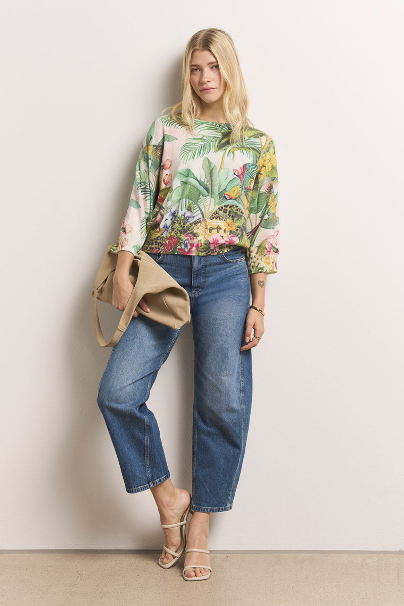 Eine Frau steht vor einer weißen Wand und trägt einen 3/4-Ärmel-Pullover mit Baumwollanteil von Princess Goes Hollywood, blaue Jeans mit Bündchen, beigefarbene Riemchensandalen und eine hellbraune Umhängetasche, während sie ihr langes blondes Haar offen trägt.