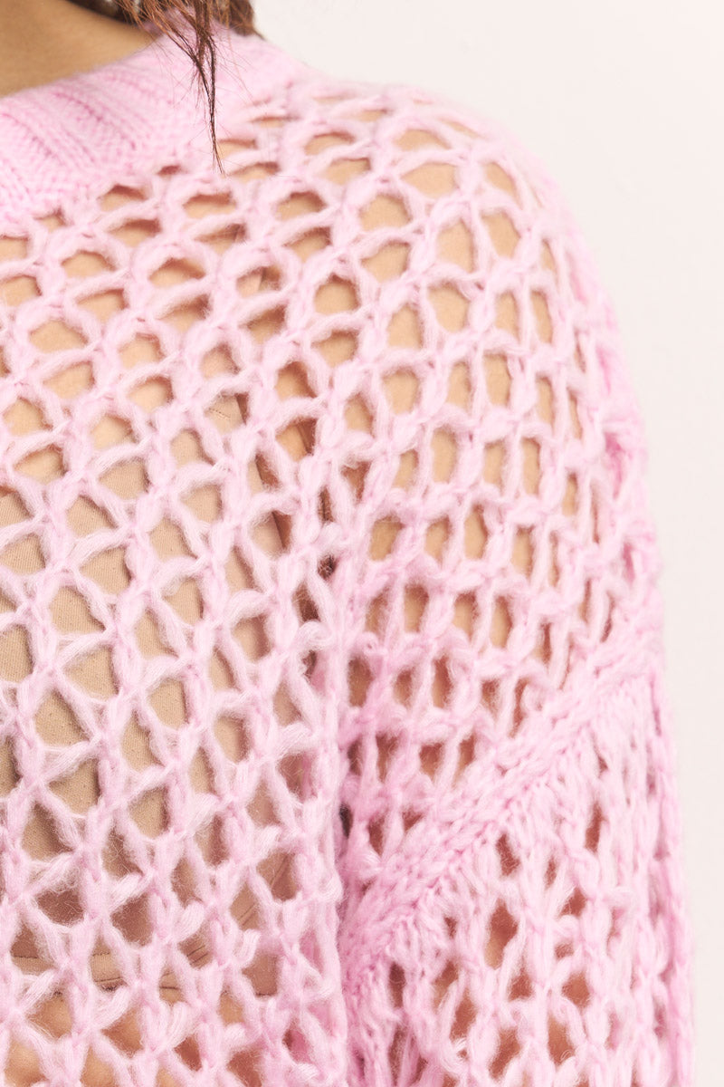 Nahaufnahme einer Person, die einen hellrosa, klobigen Lochstrick Damen Pullover von Princess Goes Hollywood trägt. Der offen gestrickte Merino-Alpaka-Mix-Pullover zeigt Haut und hat gerippte Kanten und eine weiche, kuschelige Textur.