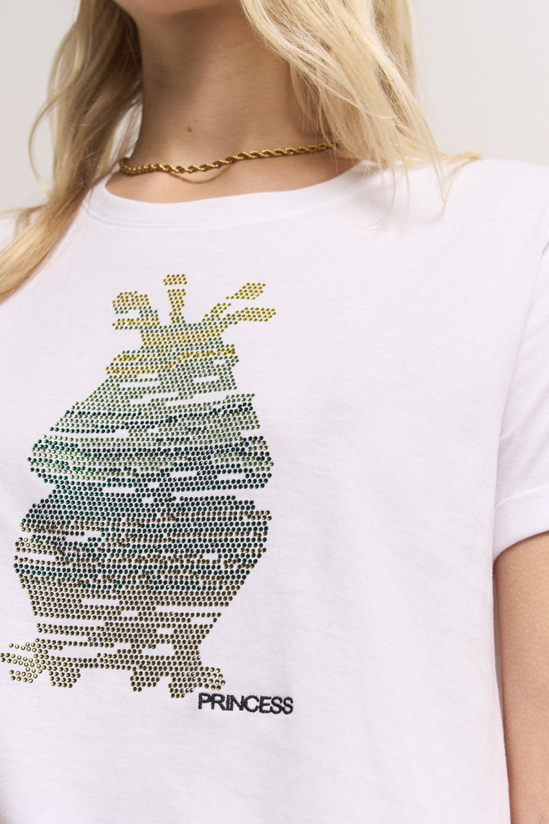 Nahaufnahme einer Person in einem weißen Baumwolle-T-Shirt von Princess Goes Hollywood mit Strass, funkelndem Ananas-Print und dem Wort PRINCESS. Die Person trägt eine goldene Kette, hat lange blonde Haare und einen neutralen, unscharfen Hintergrund.