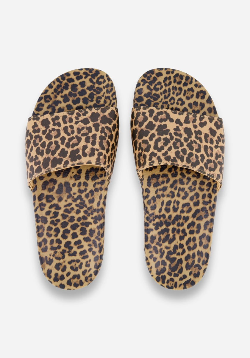 Ein Paar Princess Goes Hollywood Pantoletten mit einem auffälligen Leopardenmuster in Braun, Hellbraun und Schwarz. Diese Sommerschuhe haben breite obere Riemen und flache Sohlen, die beide das Muster aufweisen. Abgebildet von oben auf einem weißen Hintergrund.