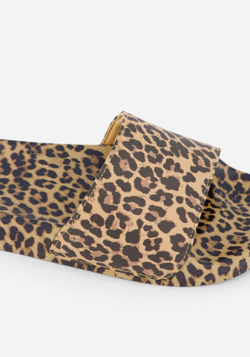 Eine Nahaufnahme der Princess Goes Hollywood Leopardenmuster Slides mit hellbraunem Grundton und auffälligem schwarz-braunem Allover-Print. Der breite Riemen spiegelt das Leopardenmuster wider und lässt diese sommerlichen Schuhe vor einem schlichten weißen Hintergrund auffallen.