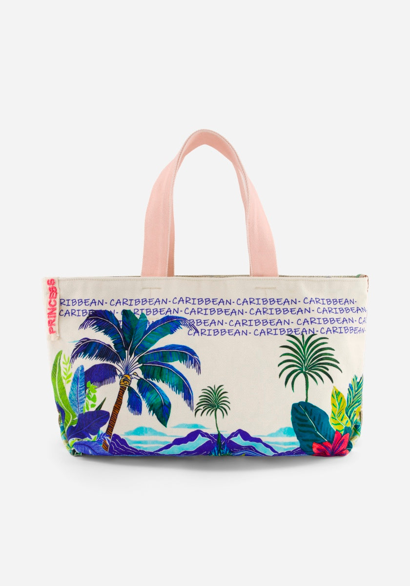 Die Princess Goes Hollywood Baumwolle Strandtasche hat blassrosa Griffe und lebhafte tropische Drucke von Palmen, Pflanzen und Bergen. Der Schriftzug "CARIBBEAN" wiederholt sich auf der Oberseite - ideal für die Flucht nach St-Barth.