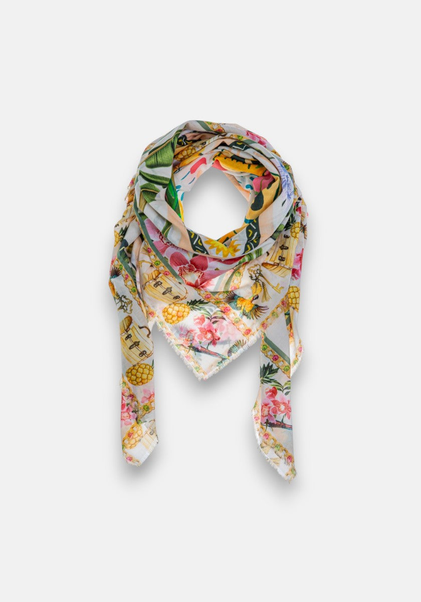 Ein quadratisches Baumwolltuch von Princess Goes Hollywood zeigt bunte Blumen, Ananas und grüne Blätter auf weißem Grund. In Dreiecksform gefaltet, fallen die leicht ausgefransten Kanten vor einem hellgrauen Hintergrund auf.