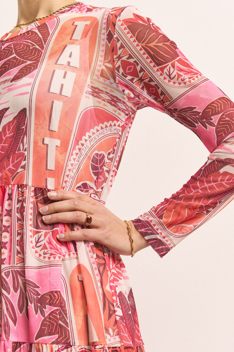 Eine Person trägt ein "Princess Goes Hollywood"-Netzkleid mit einem pinkfarbenen und roten tropischen Blätterdruck und der Aufschrift "TAHITI". Ihre linke Hand mit einem goldenen Ring und einem Kettenarmband ruht auf ihrer Taille vor einem schlichten hellen Hintergrund.