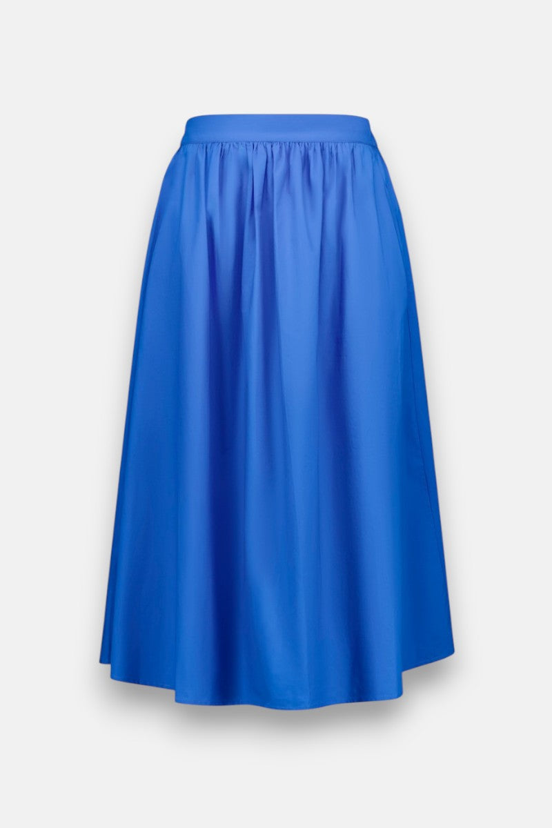 Der knielange, hellblaue Midirock von Princess Goes Hollywood hat einen taillierten Bund und zarte Falten. Er ist aus glatter, leichter Baumwolle mit dezentem Glanz gefertigt und wird vor einem schlichten, hellgrauen Hintergrund gezeigt.