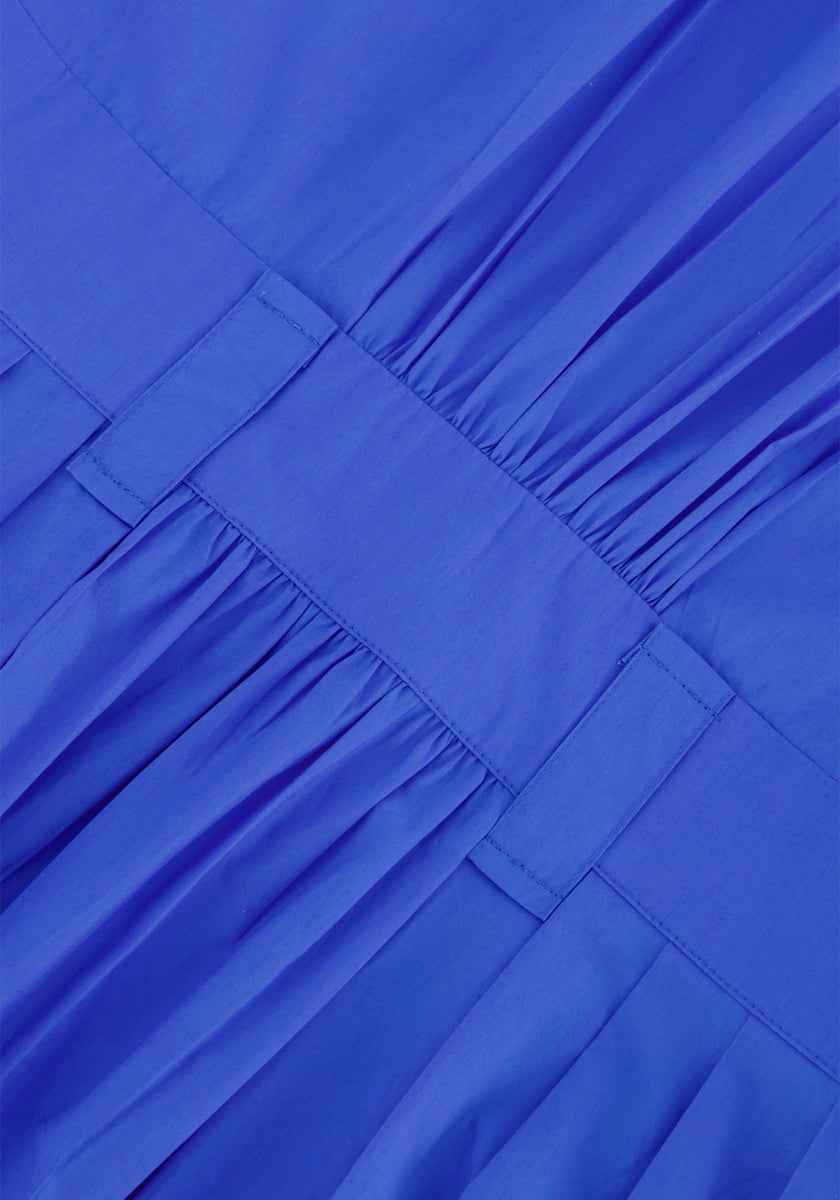 Nahaufnahme des hellblauen Baumwollstoffs von Princess Goes Hollywood mit plissierten Details und zwei horizontalen Bändern für ein maßgeschneidertes Hemdblusenkleid im Midi-Länge-Look. Die feinen Nähte und die glatte Textur sind deutlich sichtbar.