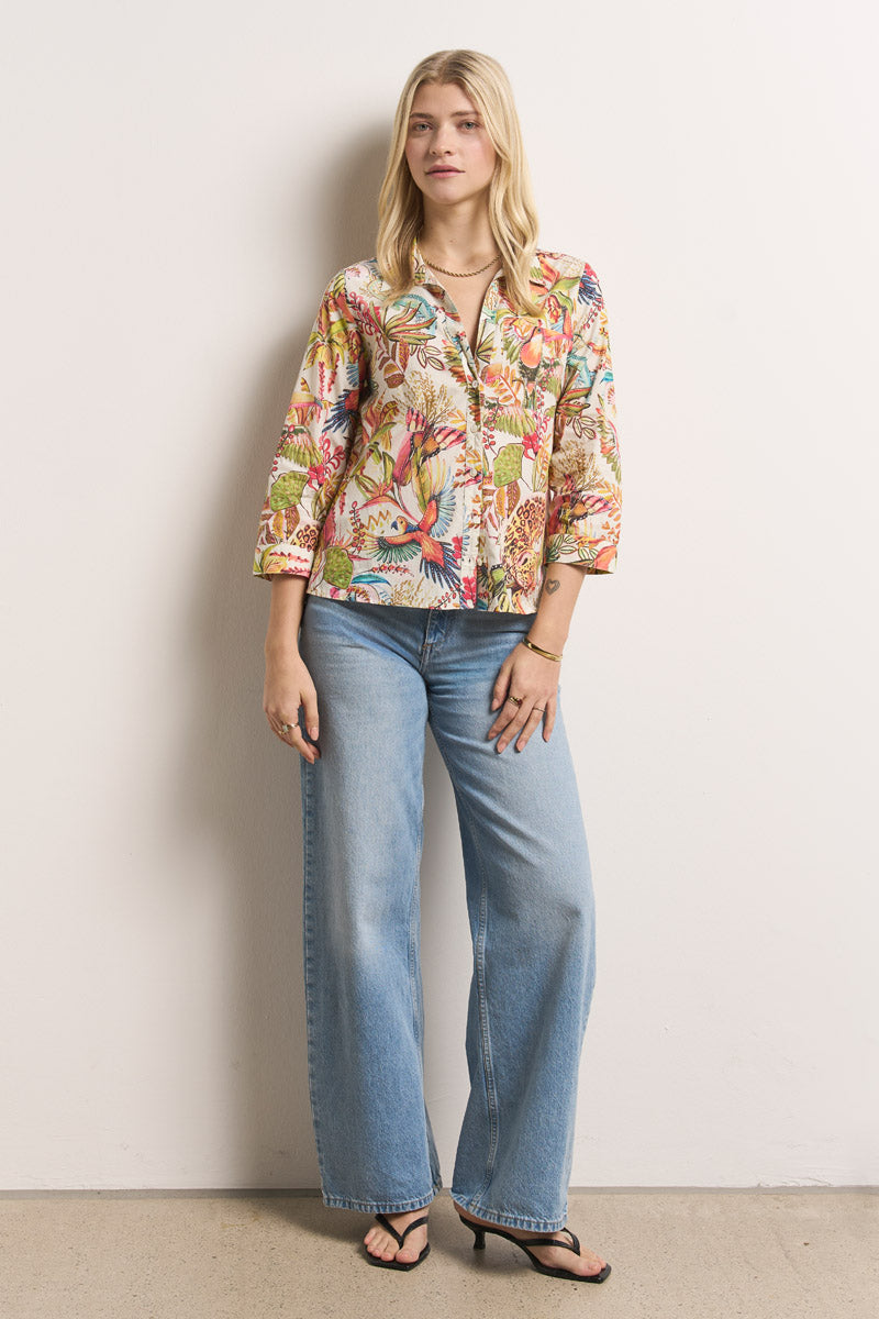 Eine Frau mit langen blonden Haaren steht vor einer weißen Wand und trägt eine Princess Goes Hollywood Hemdbluse aus Baumwolle mit Dschungeldruck und Dreiviertelärmeln, hellblaue Jeans mit weitem Bein und schwarze hochhackige Sandalen. Sie sieht entspannt aus und trägt nur wenig Schmuck.