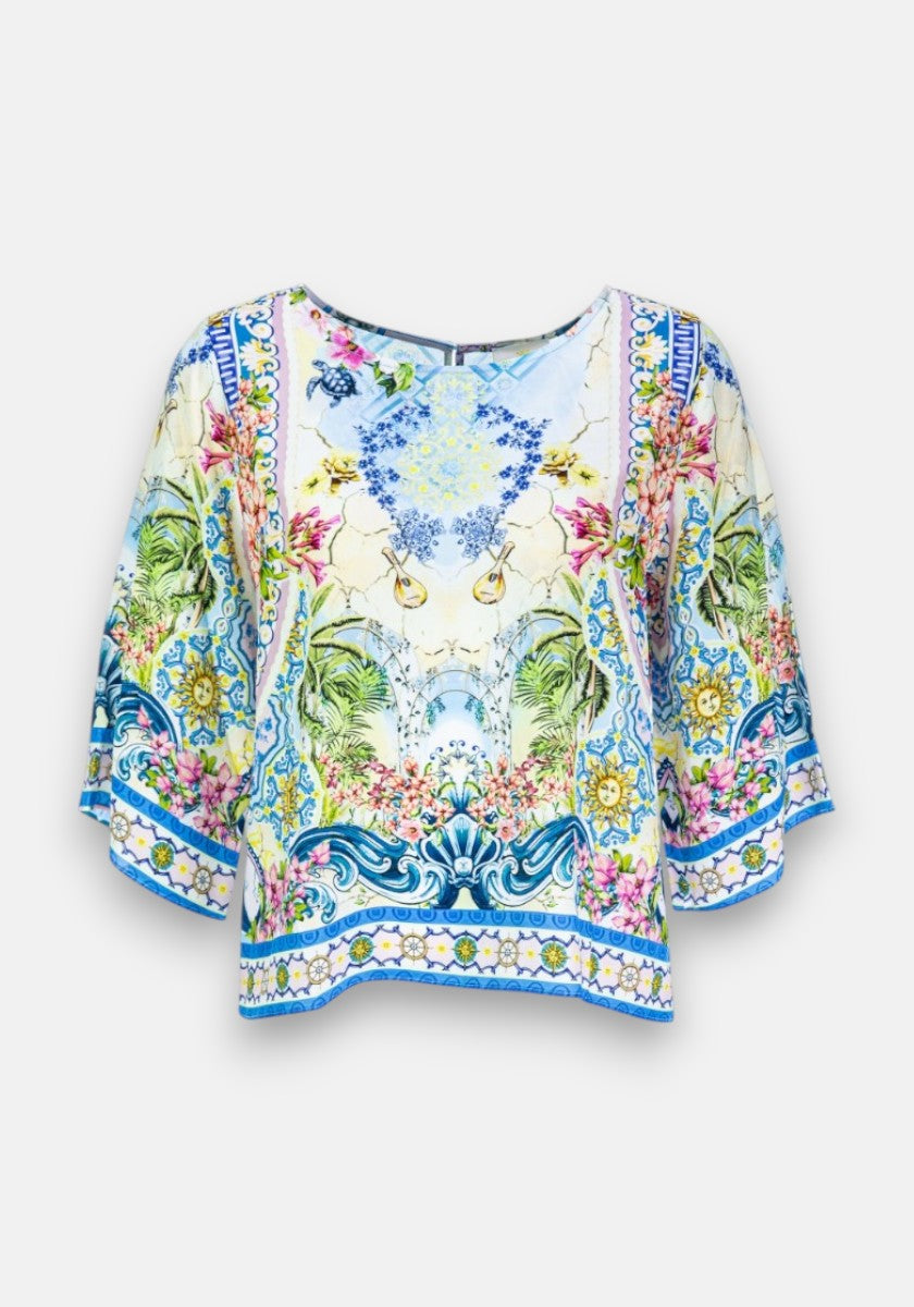 Diese lockere, kurzärmelige Seidenbluse von Princess Goes Hollywood zeigt einen leuchtenden, symmetrischen Blumen- und Botanikdruck in Blau, Grün, Gelb und Rosa mit wirbelnden Motiven und blauen Rändern auf hellem Grund.