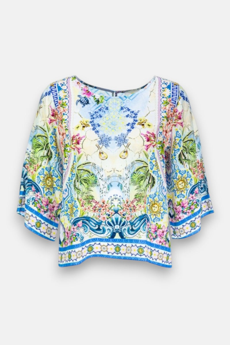 Eine lockere, kurzärmelige Seidenbluse von Princess Goes Hollywood mit Rundhalsausschnitt und einem lebhaften Landschaftsdruck mit Blumen- und Naturmotiven in Blau, Grün, Gelb und Rosa auf Hellblau für einen frischen, symmetrischen Look.